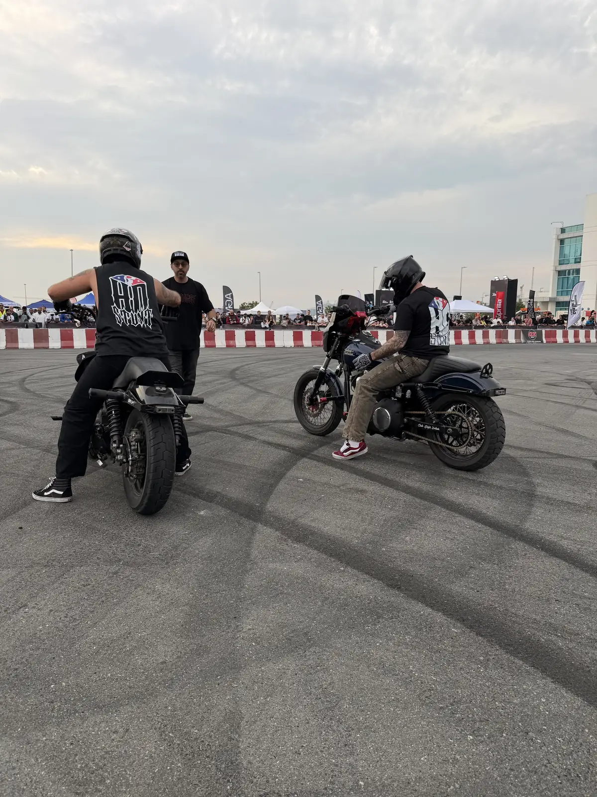 Riders on blacked-out Harleys at an open-lot meet at dusk