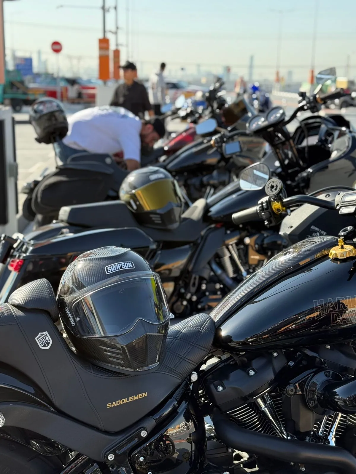 Row of blacked-out custom baggers parked at a meet, a Simpson helmet resting on the nearest seat