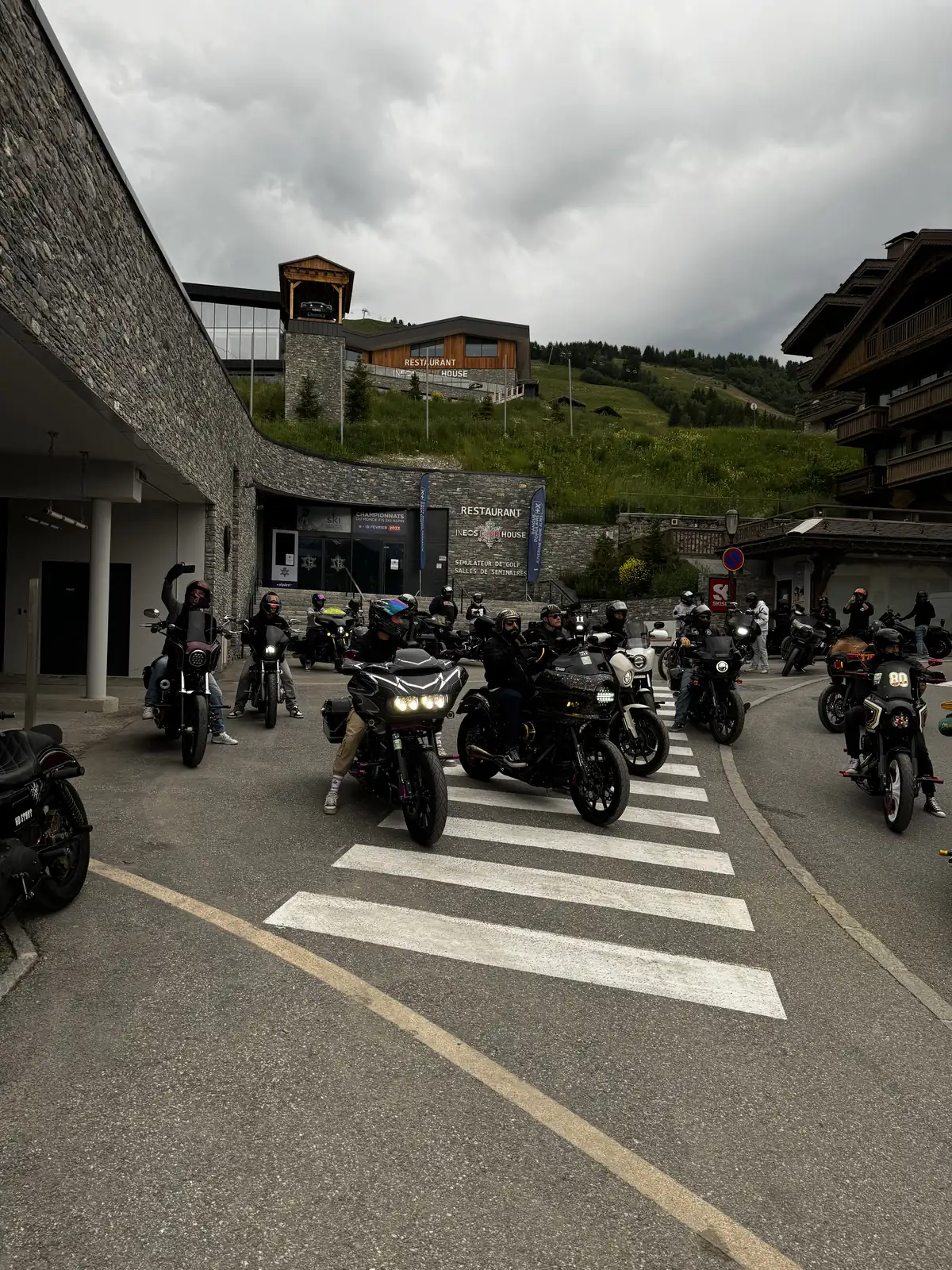 Riders parked at a mountain-village crosswalk on a group ride