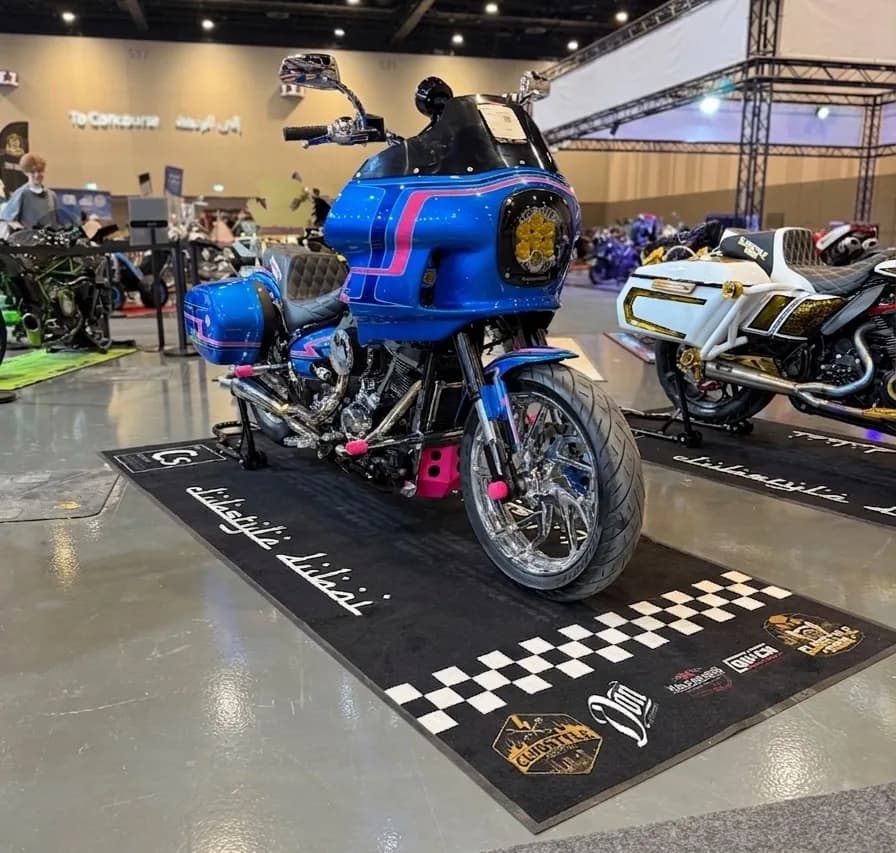 Blue-and-pink custom clubstyle bagger on a Clubstyle Dubai mat at a Dubai bike show