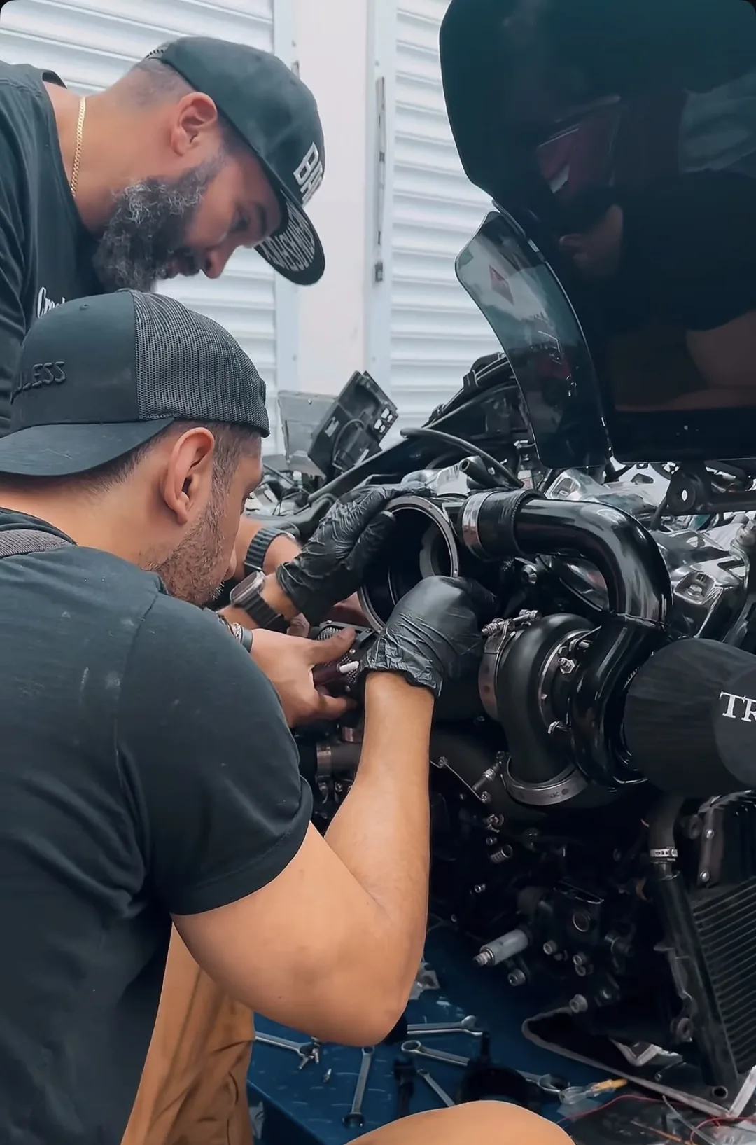 Two Forty5° builders wrenching on a turbocharged Harley engine on the workshop floor