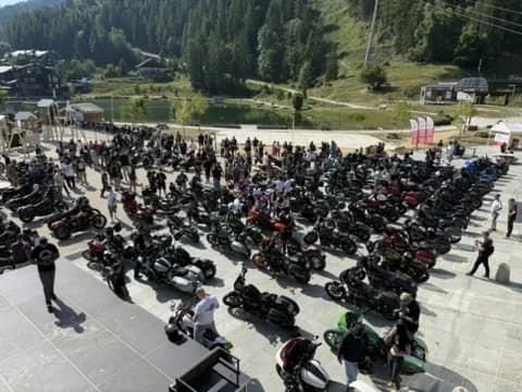 Clubstyle Harleys filling an alpine car park at a mountain meet in France