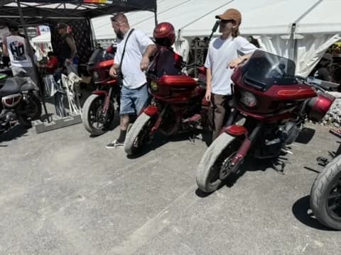 Red custom baggers lined up under the show tent at a European clubstyle event